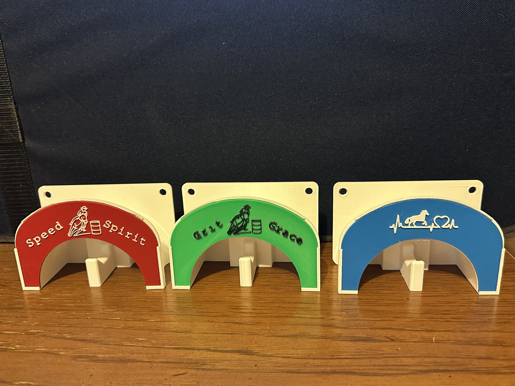 Horseshoe-shaped bridle holders in red, green, and blue with custom wording and designs