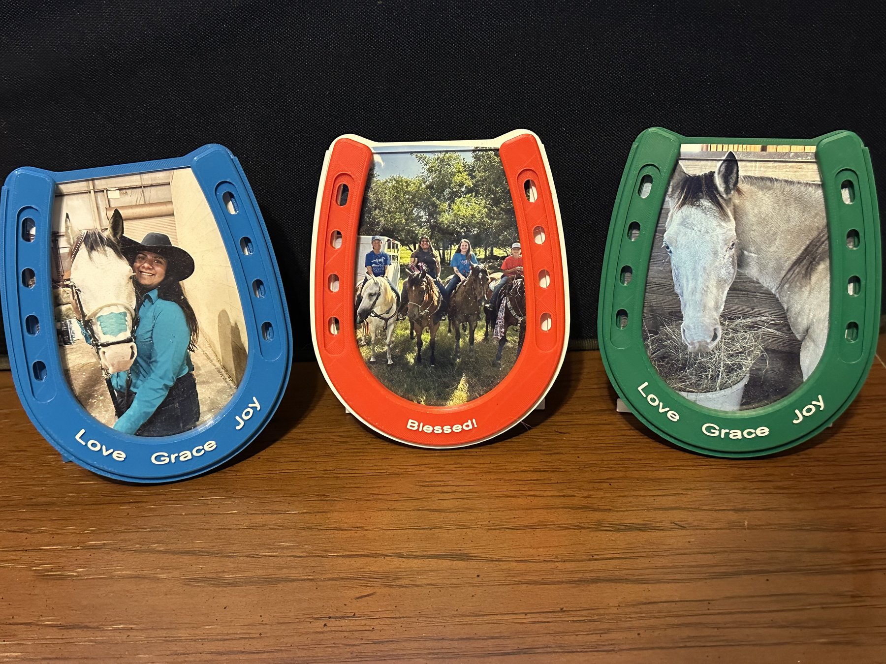 Horseshoe-shaped picture frames in blue, orange, and green with photos and custom wording